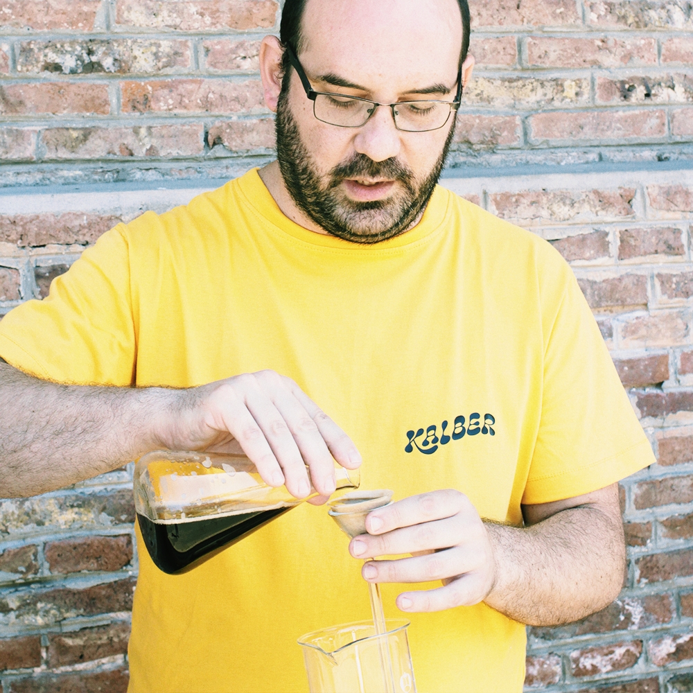 Chico de lentes y remera amarilla de la marca de la empresa. Trabajando con unos objetos de quimica