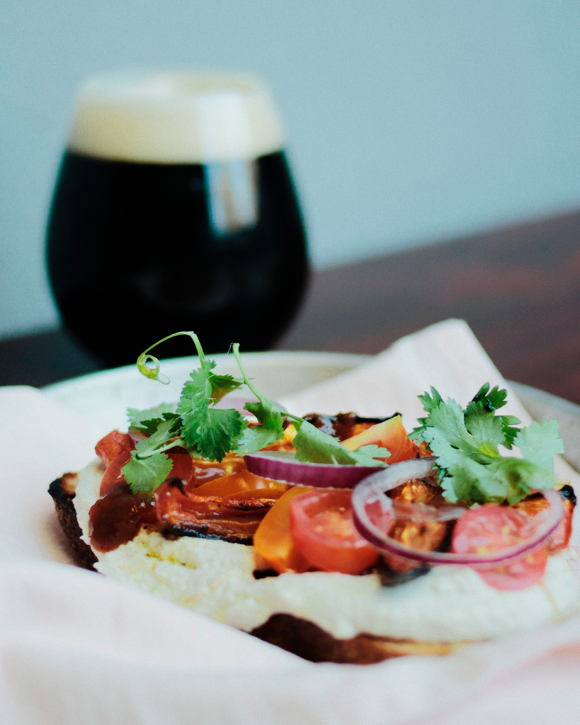 cerveza negra de fondo, tosta, queso untable, cherrys, cebolla colorada y peregil