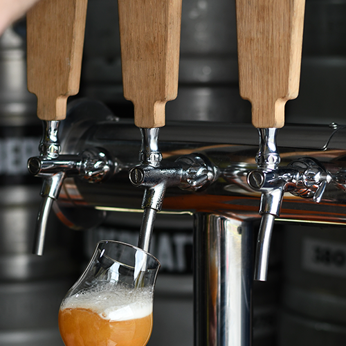 tres canillas que tiran cerveza con un vaso de cerveza sirviendose desde esa canilla